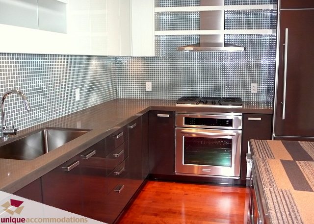Bright kitchen with dark countertops, stainless steel appliances, and hardwood floors. - 2802 - 1277 Melville Street, Vancouver Downtown
