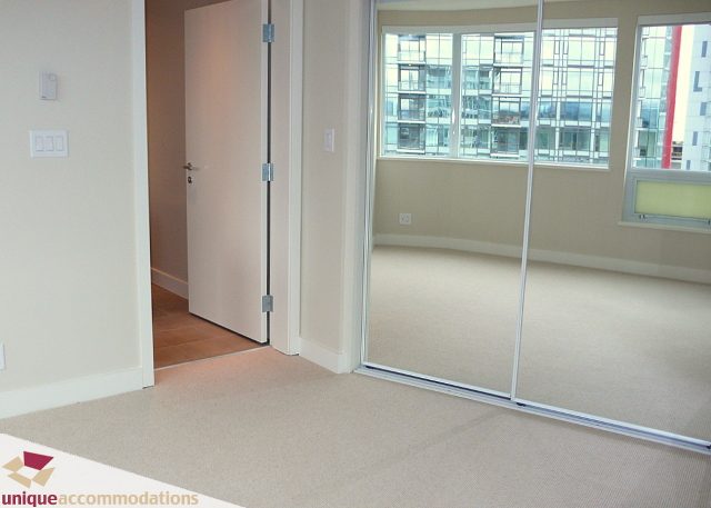 Bright living room with large windows, city view, and sliding glass doors. - 2802 - 1277 Melville Street, Vancouver Downtown