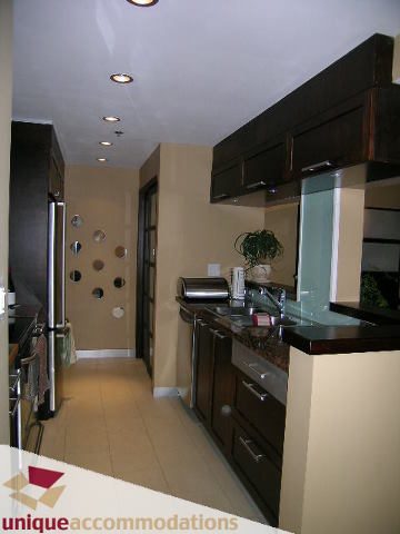 Bright kitchen with modern countertops and dark cabinets, featuring a city view. - 2803 - 930 Cambie Street, Vancouver Downtown