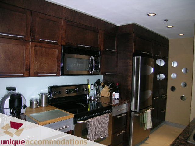 Bright kitchen with dark wood cabinets, stainless steel appliances, and granite countertops. - 2803 - 930 Cambie Street, Vancouver Downtown