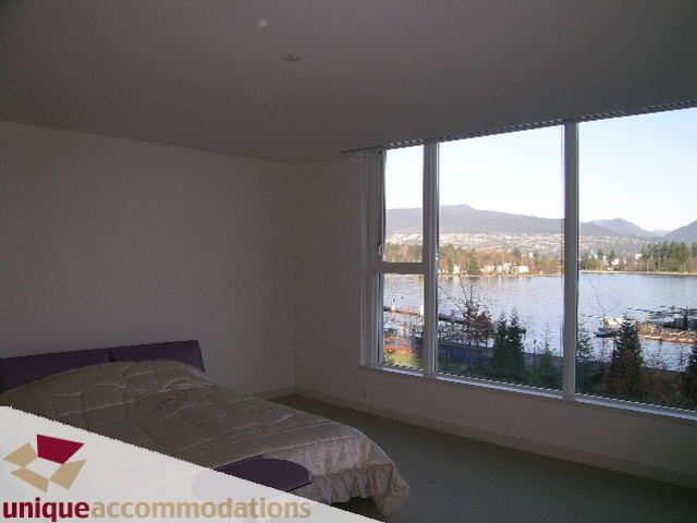 Furnished bedroom with large windows offering a stunning city view and waterfront scenery. - 104 - 1139 West Cordova Street, Vancouver Downtown