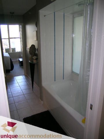 Furnished bathroom with glass shower and white tub, natural light from window. - 1806 - 969 Richards Street, Vancouver Downtown