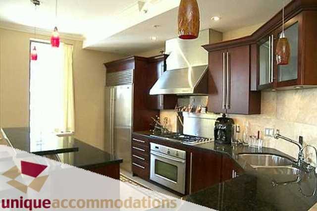 Bright kitchen with dark wood cabinets, stainless steel appliances, and granite countertops. - 403 - 499 Drake Street, Vancouver Downtown