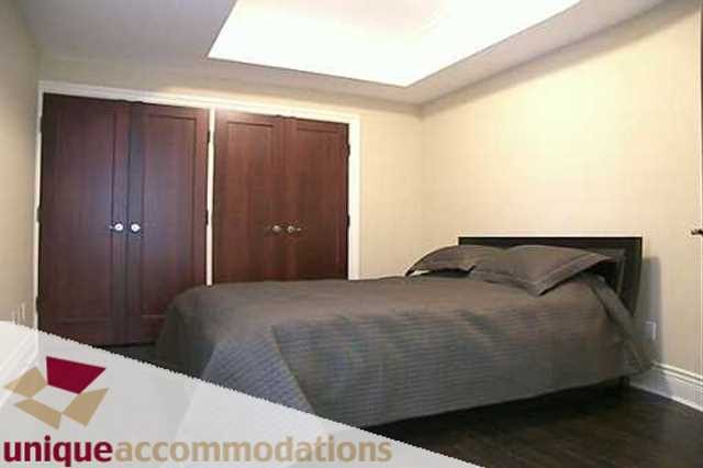 Furnished bedroom with wooden closet doors and hardwood floors. - 403 - 499 Drake Street, Vancouver Downtown