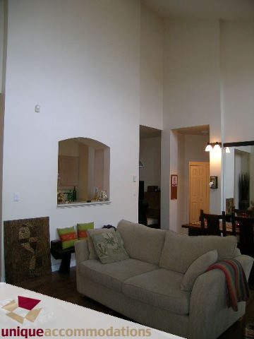 Furnished living room with beige sofa, green pillows, and wooden flooring. - 604 - 3600 Windcrest Drive, North Vancouver