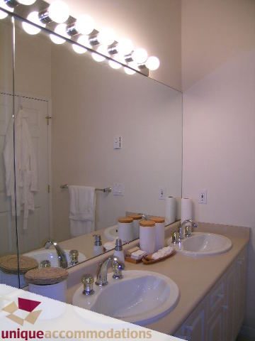 Furnished bathroom with dual sinks, countertop, and wall-mounted lights. - 604 - 3600 Windcrest Drive, North Vancouver