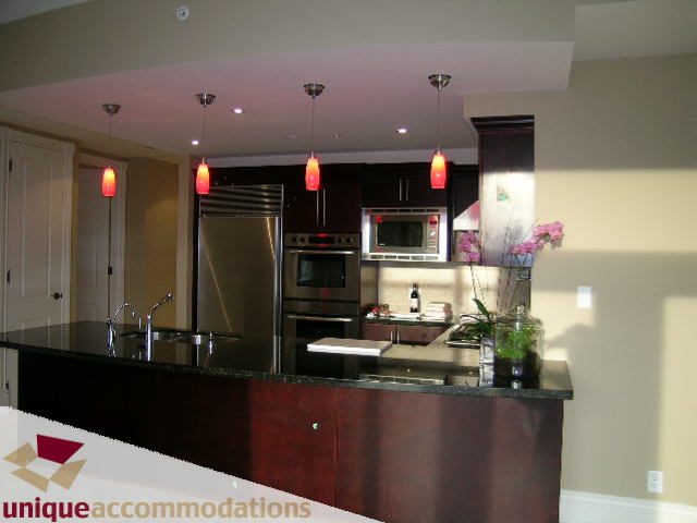 Bright kitchen with dark wood cabinets, stainless steel appliances, and red pendant lights. - 1901 - 1280 Richards Street, Vancouver Downtown