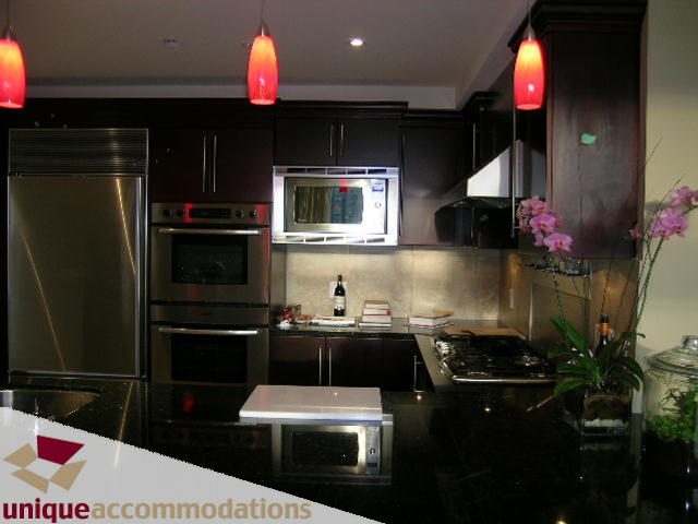 Bright kitchen with granite countertops, stainless steel appliances, and red pendant lights. - 1901 - 1280 Richards Street, Vancouver Downtown