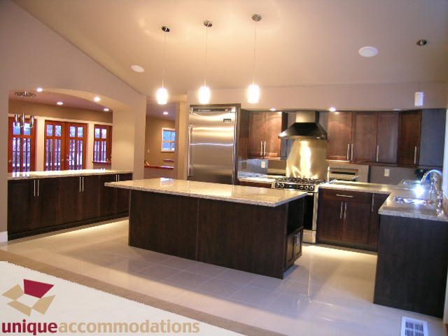 Bright kitchen with dark wood cabinets, granite countertops, and modern lighting fixtures. - 811 Huntingdon Crescent, North Vancouver