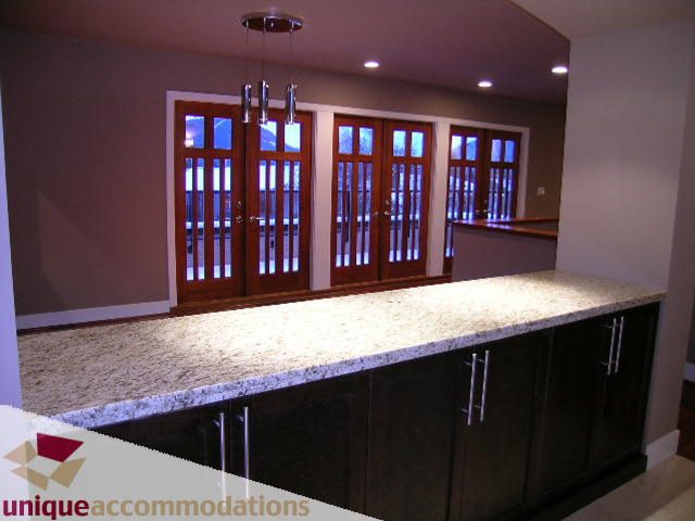 Bright kitchen with granite countertops and wooden cabinets, featuring a city view through the doors. - 811 Huntingdon Crescent, North Vancouver