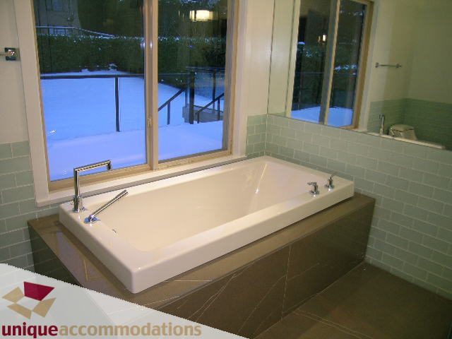 Modern bathroom with white sink, green tiles, and a view of the backyard. - 811 Huntingdon Crescent, North Vancouver