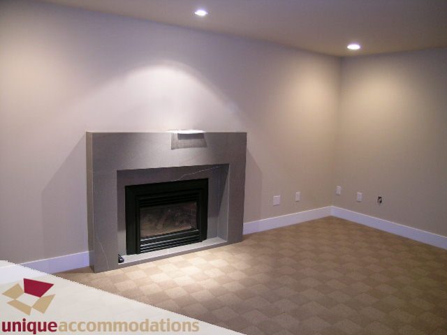 Living room with modern fireplace, neutral tones, and recessed lighting. - 811 Huntingdon Crescent, North Vancouver