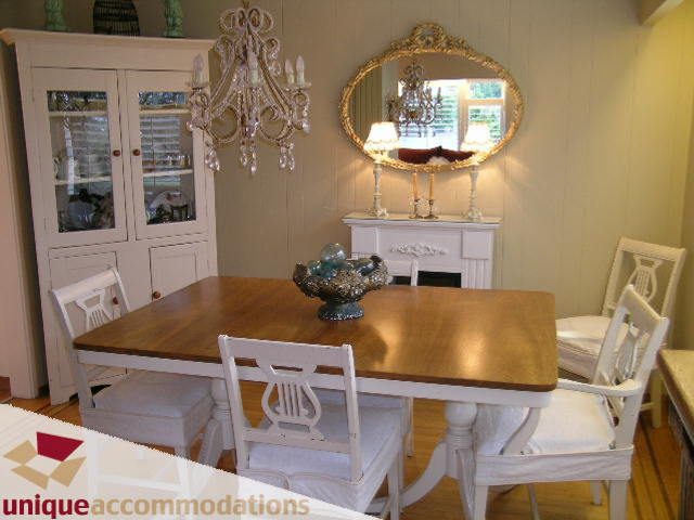 Dining room with wooden table, white chairs, chandelier, and mirror. - 840 16th Street, West Vancouver