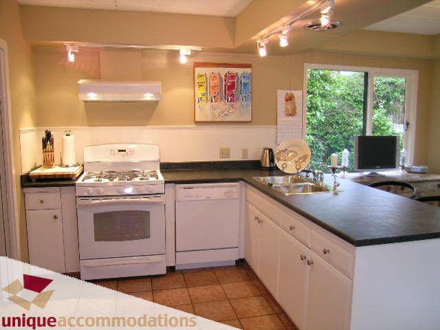 Bright kitchen with white cabinetry, black countertops, and a view of greenery outside. - 840 16th Street, West Vancouver