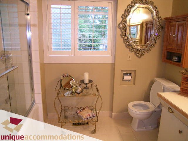 Bright bathroom with white fixtures, ornate mirror, and window with shutters. - 840 16th Street, West Vancouver