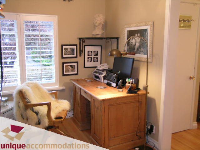 Bright home office with wooden desk, framed photos, and a cozy chair. - 840 16th Street, West Vancouver