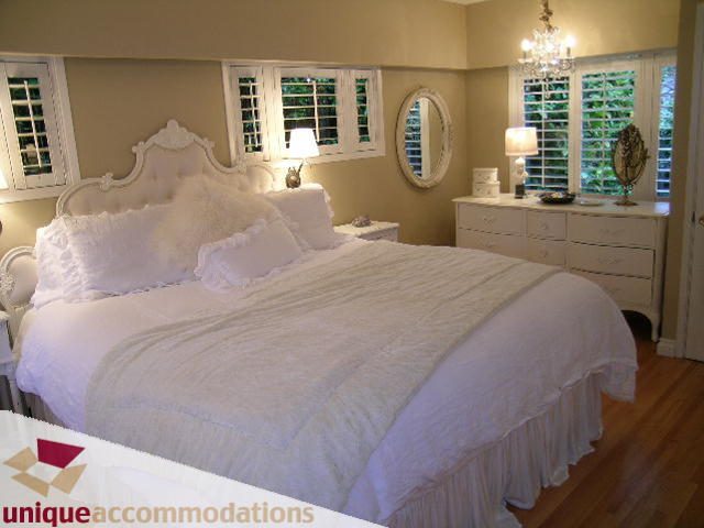 Spacious bedroom with white bedding, hardwood floors, and large windows. - 840 16th Street, West Vancouver