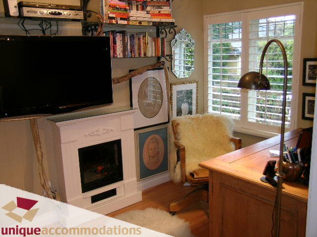 Bright living room with hardwood floors, bookshelves, and a large window with shutters. - 840 16th Street, West Vancouver