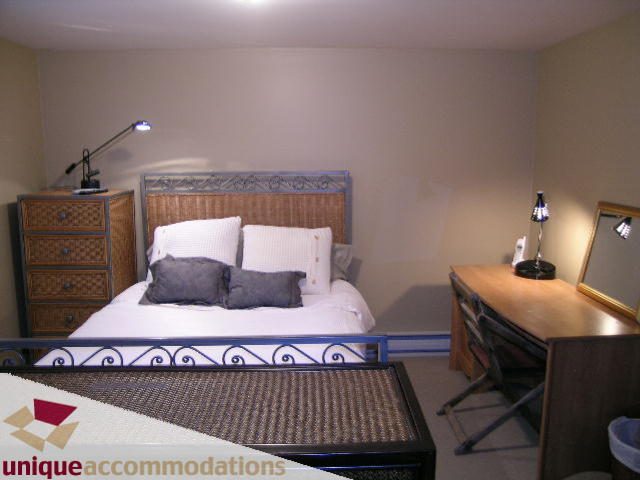Furnished bedroom with wicker headboard, blue accents, and desk setup. - 840 16th Street, West Vancouver