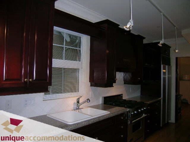Bright kitchen with dark wood cabinets, granite countertops, and stainless steel appliances. - 1055 West 15th Avenue, Vancouver West Side