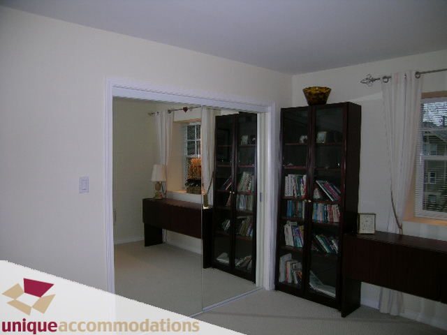Living room with dark wood bookshelves and a glass-enclosed corner unit. - 1055 West 15th Avenue, Vancouver West Side
