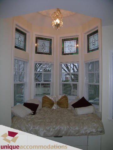 Furnished bedroom with bay window, stained glass, and plush bedding. - 1055 West 15th Avenue, Vancouver West Side