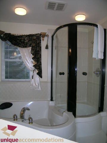 Spacious bathroom with a corner shower and a bathtub, featuring a window with blinds and a curtain. - 1055 West 15th Avenue, Vancouver West Side