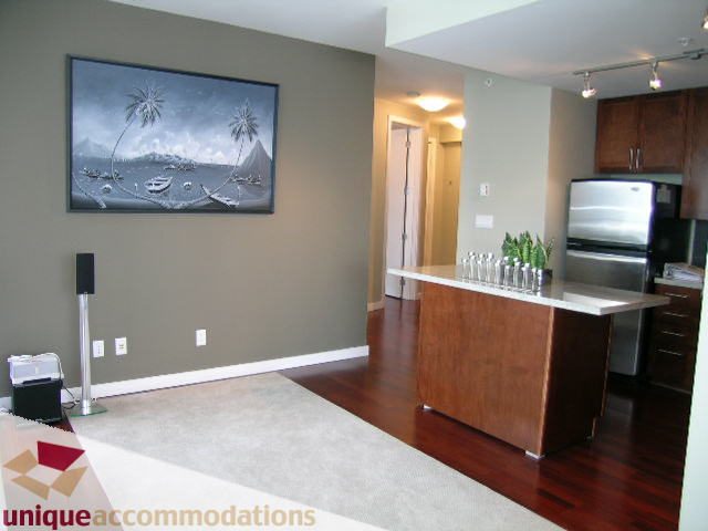 Bright living room with hardwood floors, modern kitchen, and large artwork on the wall. - 702 - 2055 Yukon Street, Vancouver West Side