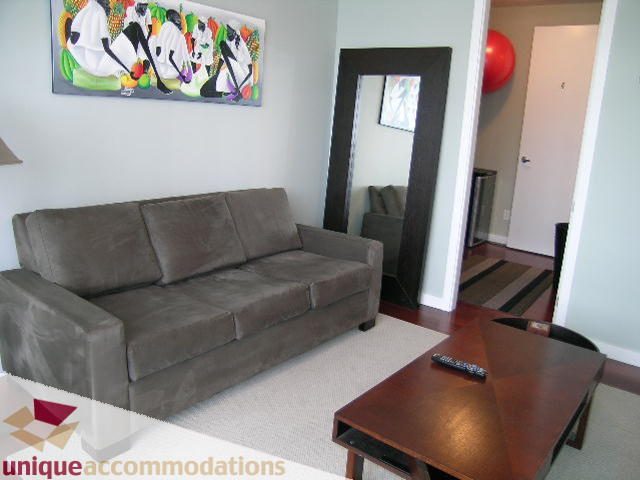 Furnished living room with a grey sectional sofa and a wooden coffee table. - 702 - 2055 Yukon Street, Vancouver West Side