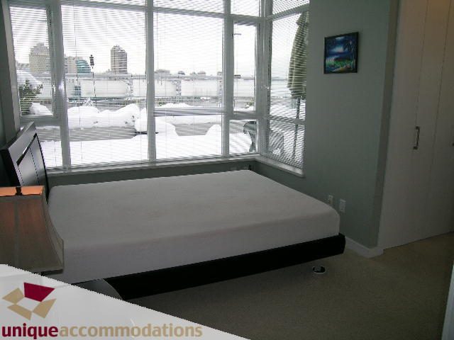 Bright bedroom with large windows offering a city view, modern furnishings, and a cozy ambiance. - 702 - 2055 Yukon Street, Vancouver West Side
