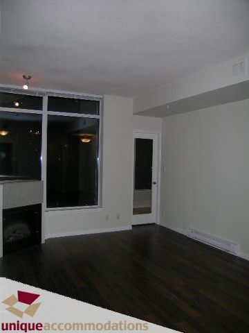 Spacious living room with hardwood floors and large windows, perfect for downtown city views. - 2701 - 1211 Melville Street, Vancouver Downtown