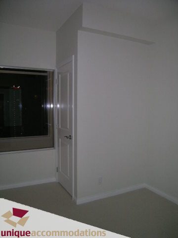 Spacious bedroom with large window, city view, and neutral decor. - 2701 - 1211 Melville Street, Vancouver Downtown