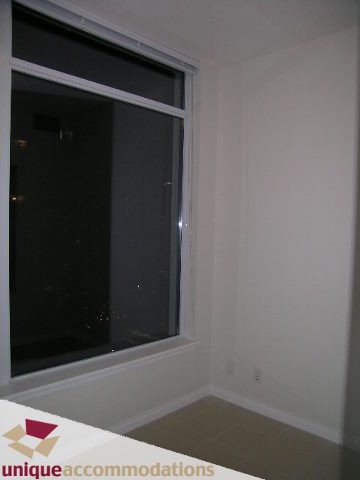 Spacious living room with large windows offering a city view and hardwood floors. - 2701 - 1211 Melville Street, Vancouver Downtown
