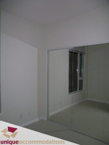 Spacious bedroom with mirrored closet doors and ample wall space. - 2701 - 1211 Melville Street, Vancouver Downtown