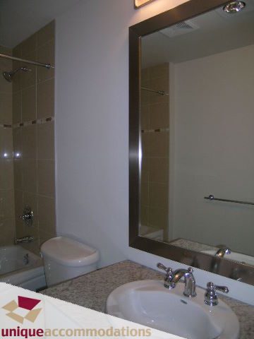 Modern bathroom with granite countertops and a large mirror. - 2701 - 1211 Melville Street, Vancouver Downtown