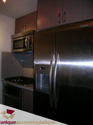 Modern kitchen with stainless steel appliances and dark cabinetry. - 2701 - 1211 Melville Street, Vancouver Downtown