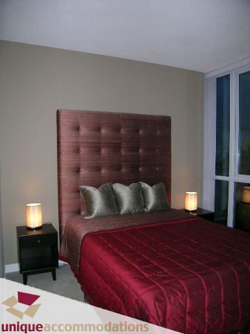 Spacious bedroom with red bedding and large headboard, nightstands with lamps. - 4201 - 1408 Strathmore Mews, Vancouver Downtown
