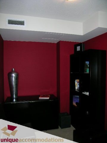 Furnished living room with dark red walls, black shelving, and a sleek black entertainment unit. - 4008 - 1408 Strathmore Mews, Vancouver Downtown