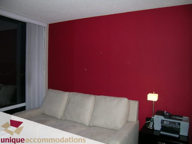 Furnished living room with red walls, beige sofa, and city view through window. - 4008 - 1408 Strathmore Mews, Vancouver Downtown