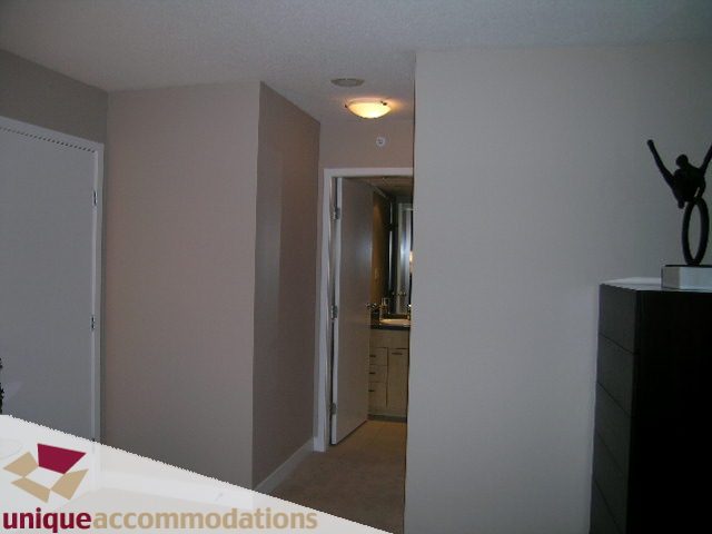 Bright hallway leading to a kitchen with white countertops and a modern sculpture on the wall. - 4008 - 1408 Strathmore Mews, Vancouver Downtown