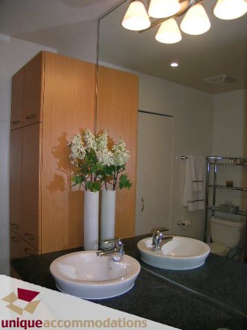 Furnished bathroom with modern sink, wooden cabinets, and large mirror. - 109 - 530 Raven Woods seasons south, North Vancouver
