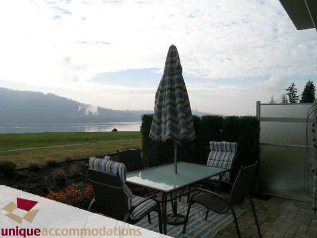 Furnished patio with table, chairs, and umbrella, overlooking a scenic view. - 109 - 530 Raven Woods seasons south, North Vancouver