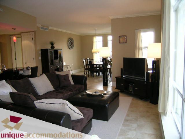 Furnished living room with comfortable couches, large windows, and a modern TV setup. - 1702 - 1280 Richards Street, Vancouver Downtown