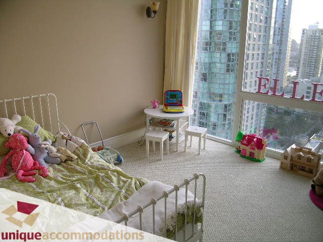 Bright bedroom with city view and cozy bedding, featuring a small desk and stuffed toys. - 1702 - 1280 Richards Street, Vancouver Downtown