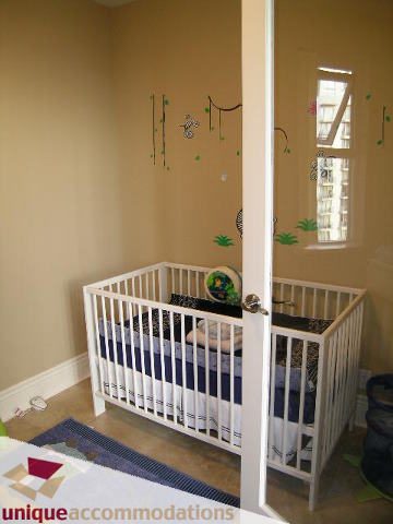 Bright nursery with white crib, blue bedding, and jungle-themed wall decals. - 1702 - 1280 Richards Street, Vancouver Downtown