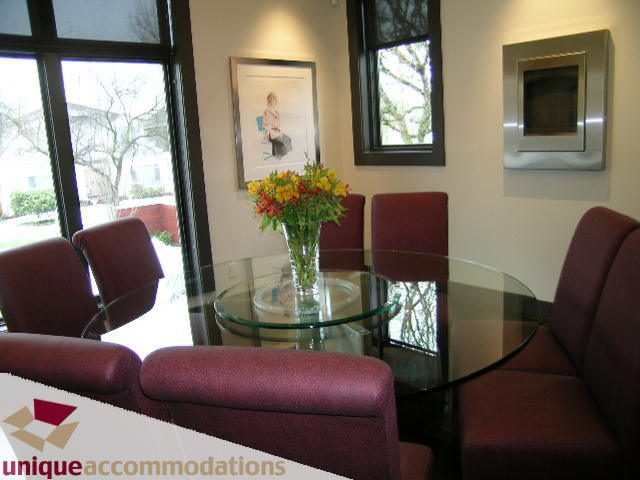 Furnished living room with glass coffee table, red armchairs, and a vase of flowers. - 2429 West 19th Avenue, Vancouver West Side