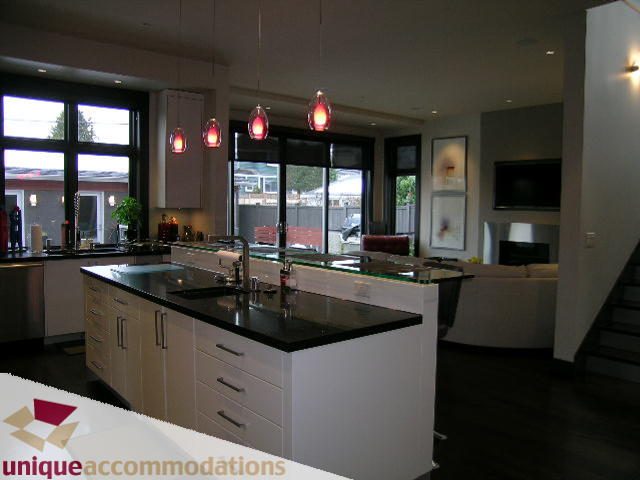 Bright kitchen with modern white cabinetry, black countertops, and red pendant lights. - 2429 West 19th Avenue, Vancouver West Side