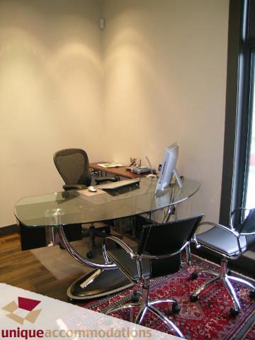 Modern office space with glass desk and ergonomic chairs, hardwood floors, and a red patterned rug. - 2429 West 19th Avenue, Vancouver West Side