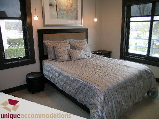 Furnished bedroom with striped bedding and large windows offering city views. - 2429 West 19th Avenue, Vancouver West Side