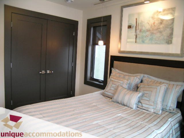 Spacious bedroom with striped bedding and dark wood closet doors. - 2429 West 19th Avenue, Vancouver West Side